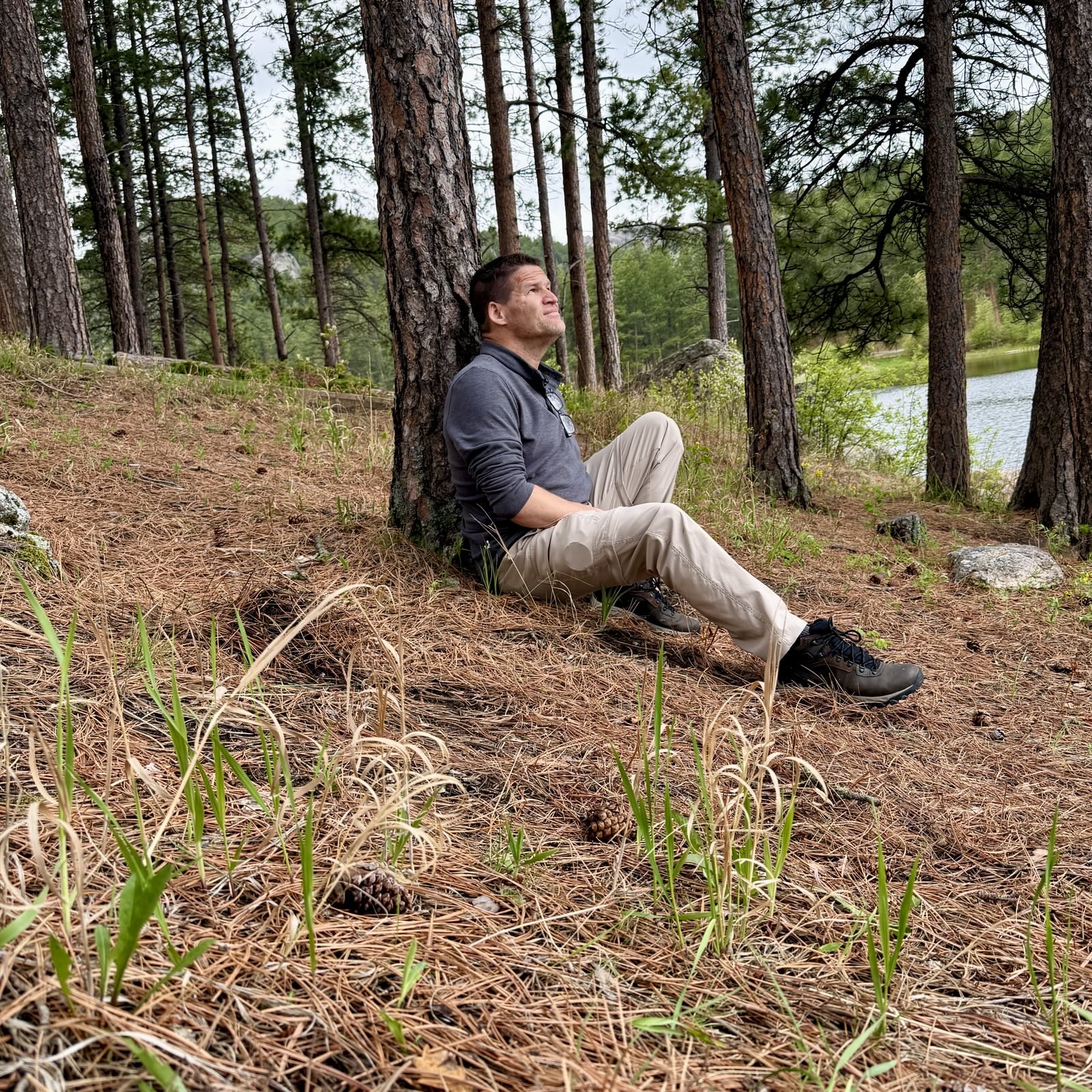 hiker sitting against tree in pine forest